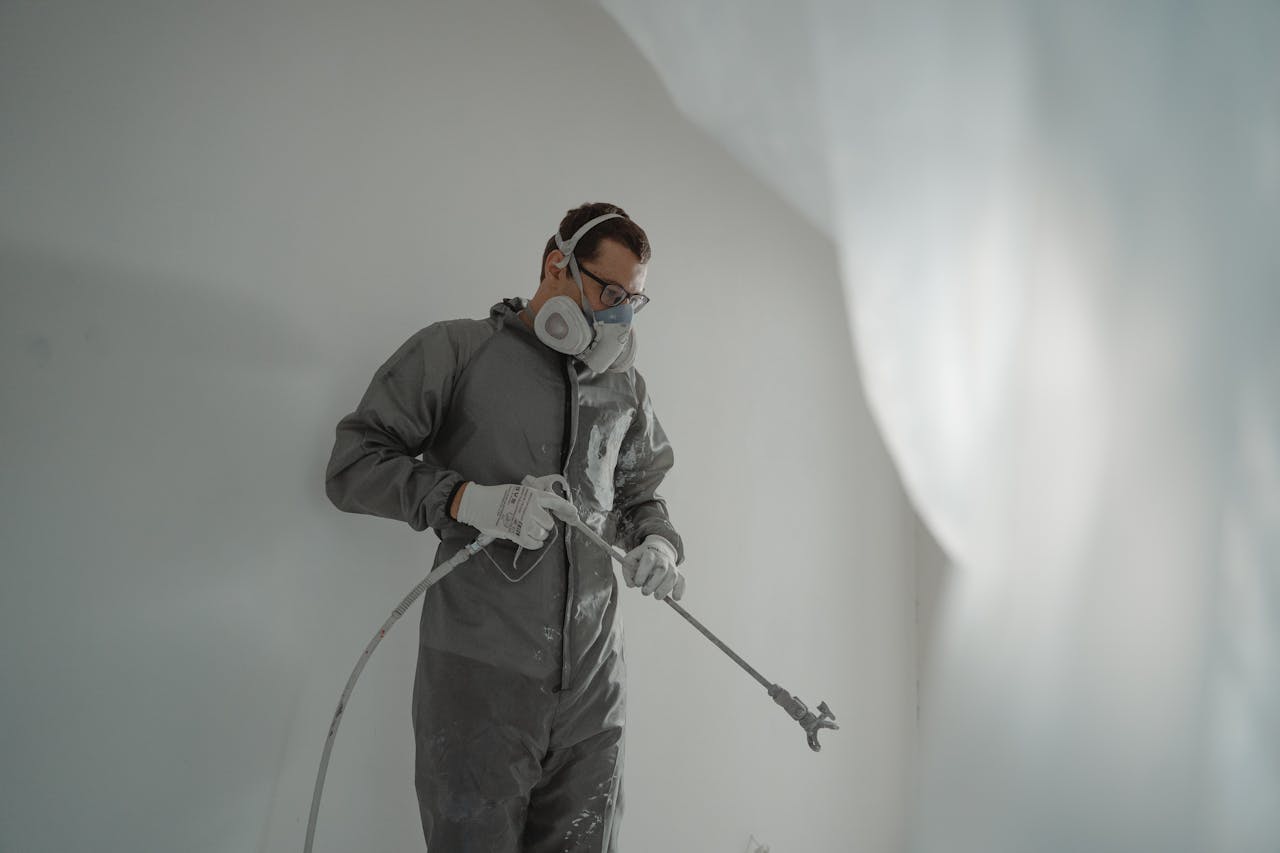 our-story Person in protective gear painting a wall, showcasing house renovation work.